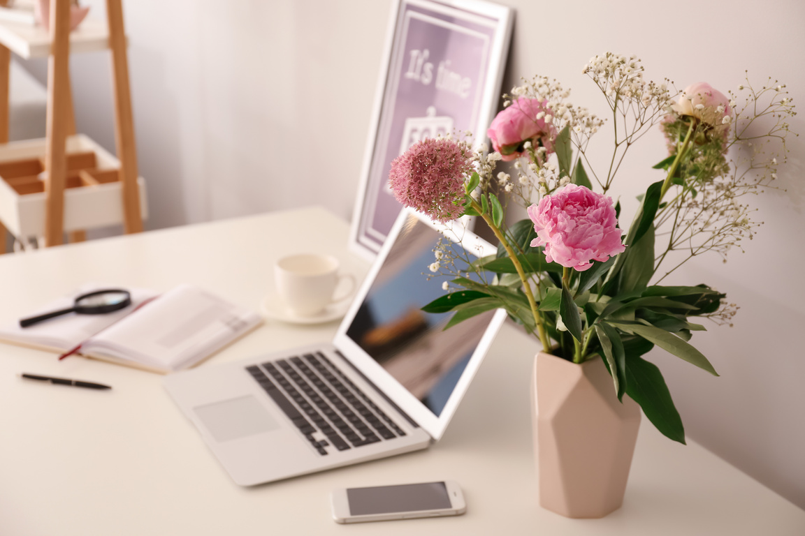 Vase with Beautiful Pink Flowers and Laptop on Table
